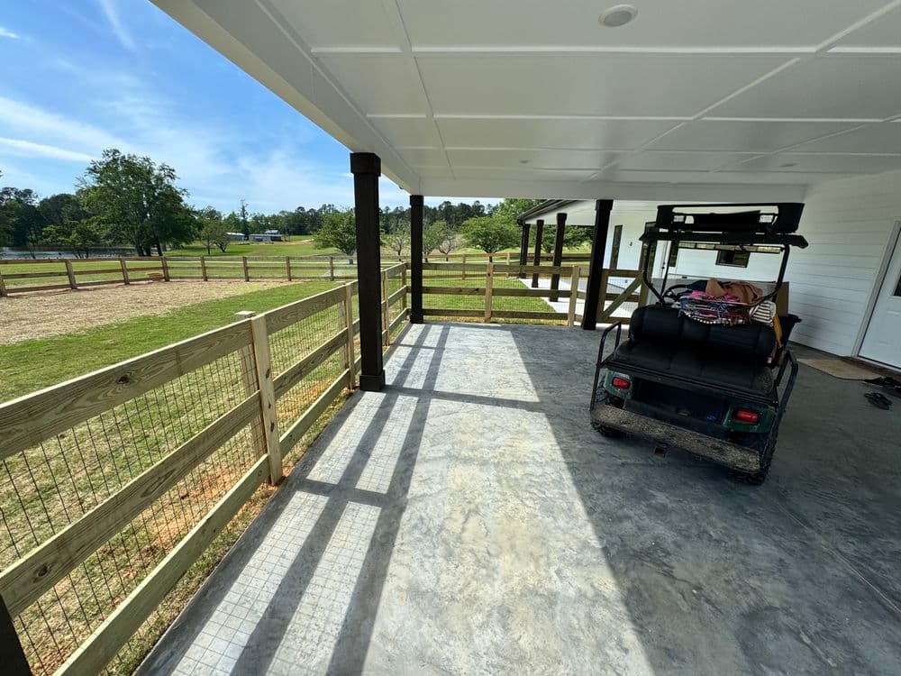 Covered porch with a utility vehicle, fenced yard, and scenic outdoor view.
