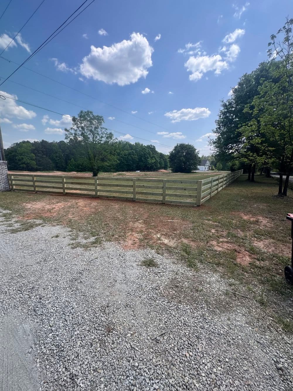 New wooden fence enclosing a grassy area under a blue sky with clouds. Perfect for outdoor spaces.
